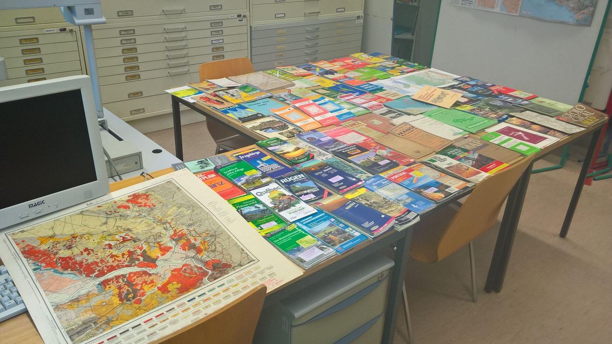 Verschiedene Exemplare der Kartensammlung der Universität Leipzig auf einem Tisch ausgebreitet.