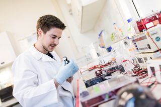 Ein männlicher Forscher führt ein biochemisches Experiment im Labor durch und arbeitet mit einer Pipette und Reagenzgläsern.