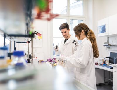 Ein Mann und eine Frau stehen im Labor und arbeiten mit wissenschaftlichen Instrumenten.