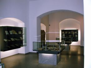 Blick in einen gewölbeartigen Raum mit einigen Vitrinen, die offenbar Schriftstücke zeigen